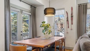 A dining area with a wooden table, chairs, a vase with flowers, and a hanging light fixture. - The Moose Lodge - New 2BR, Walk to PCMR / Main St! (Park City)
