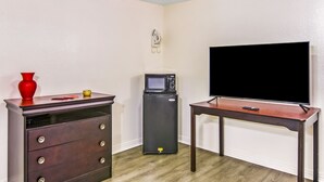 Una habitación con un aparador de madera, un refrigerador pequeño y un televisor sobre un soporte de madera.