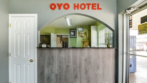 Una zona de recepción con un mostrador de madera, una puerta blanca y un cartel que dice "OYO HOTEL".