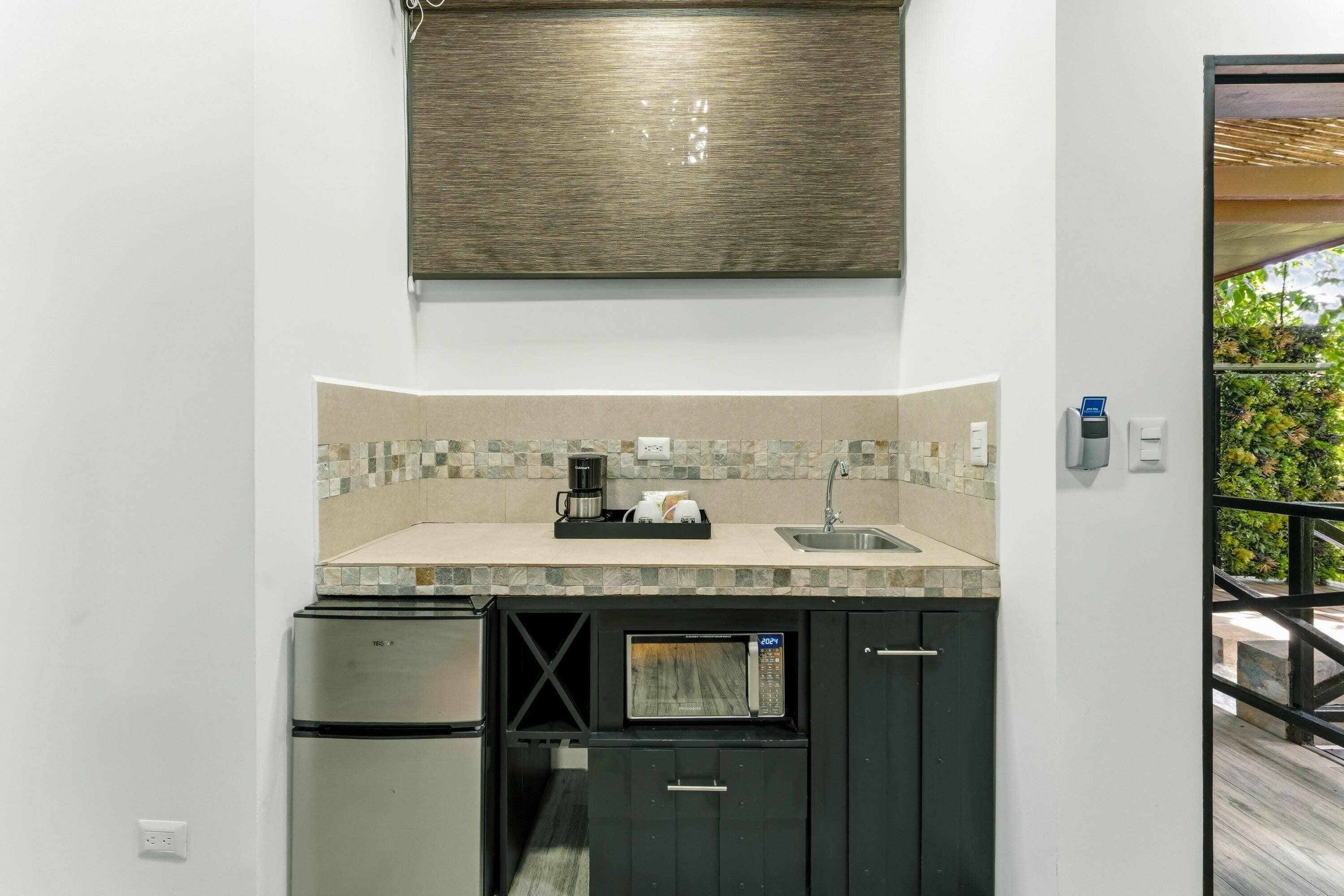 A compact kitchen with a built-in microwave, a coffee maker, and a sink.