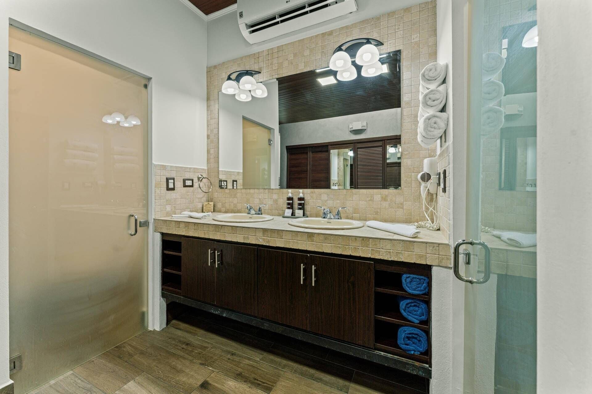 A modern bathroom with two sinks, a large mirror, and a towel rack.