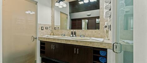 A modern bathroom with two sinks, a large mirror, and a towel rack.