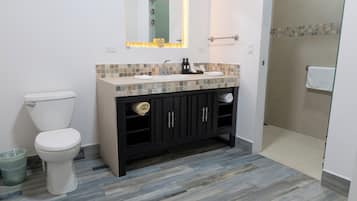 Un baño con inodoro, lavamanos y zona de ducha.