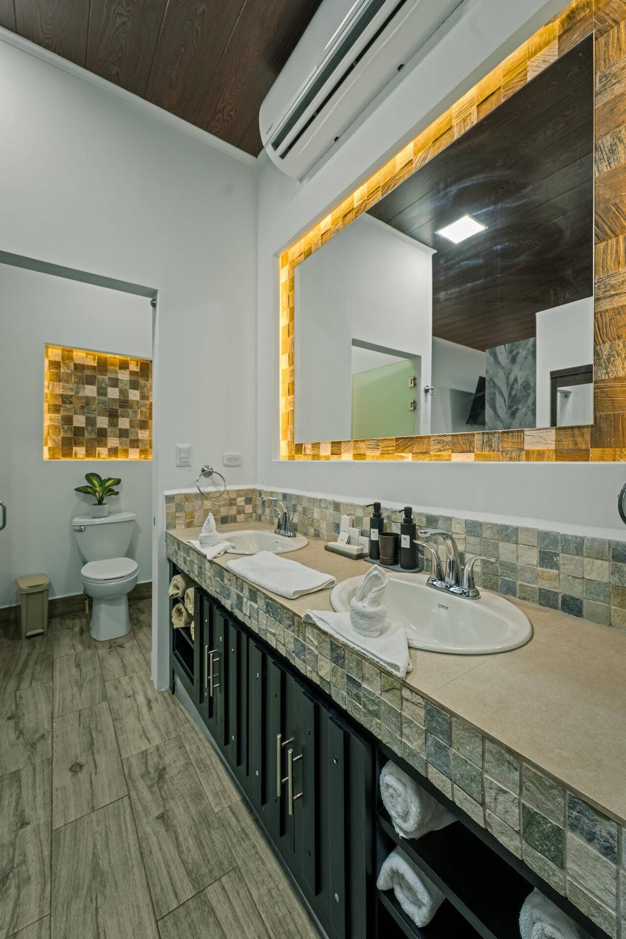 A modern bathroom with two sinks, a large mirror, and a wooden ceiling.