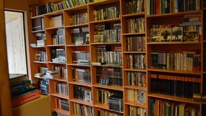 Uma biblioteca com várias estantes de madeira repletas de livros.
