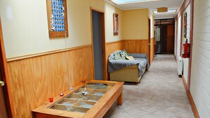 Um corredor com uma mesa de madeira, um sofá e um extintor de incêndio na parede.