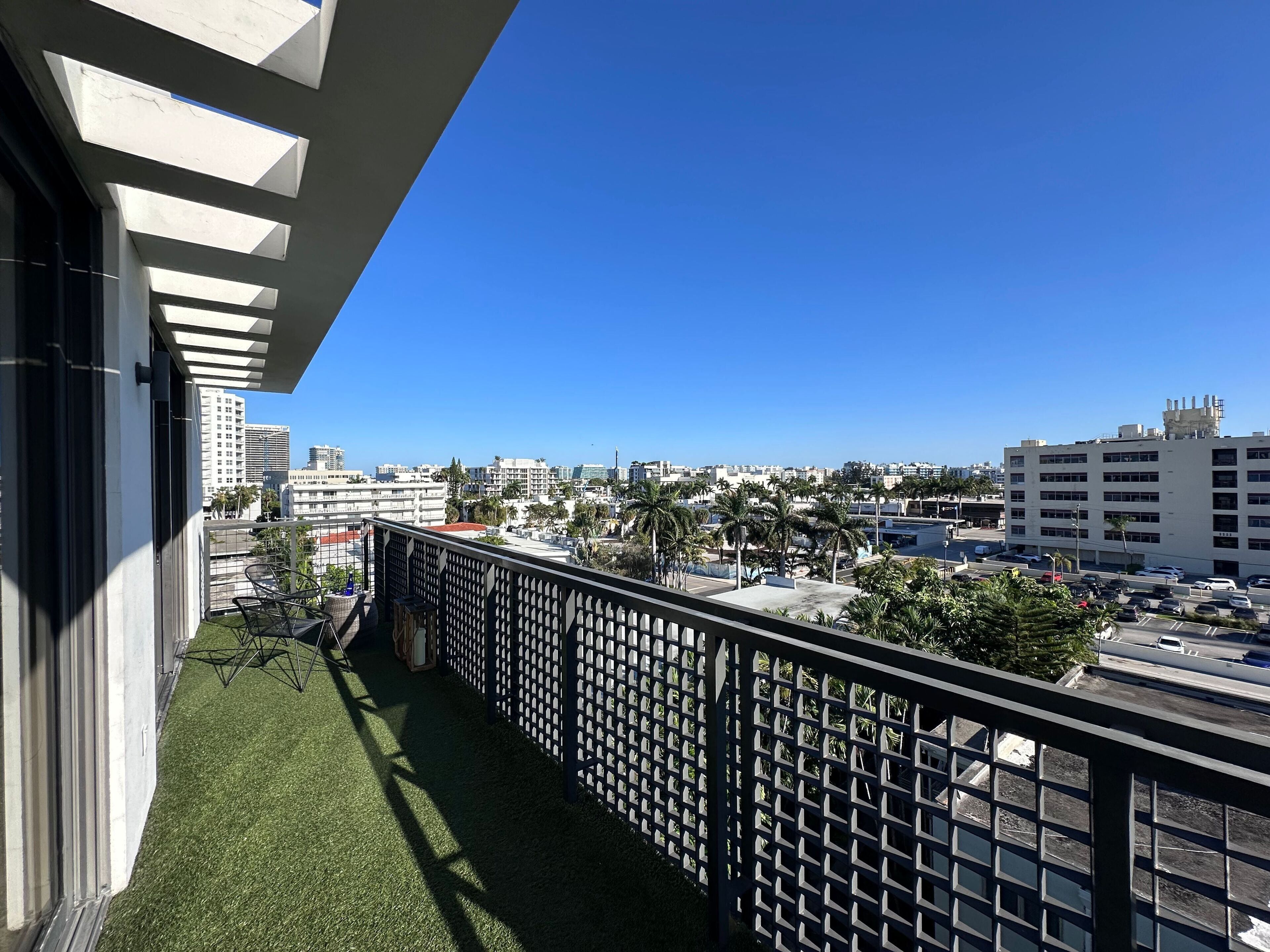 A balcony with a view of a cityscape, including buildings and a parking area.
