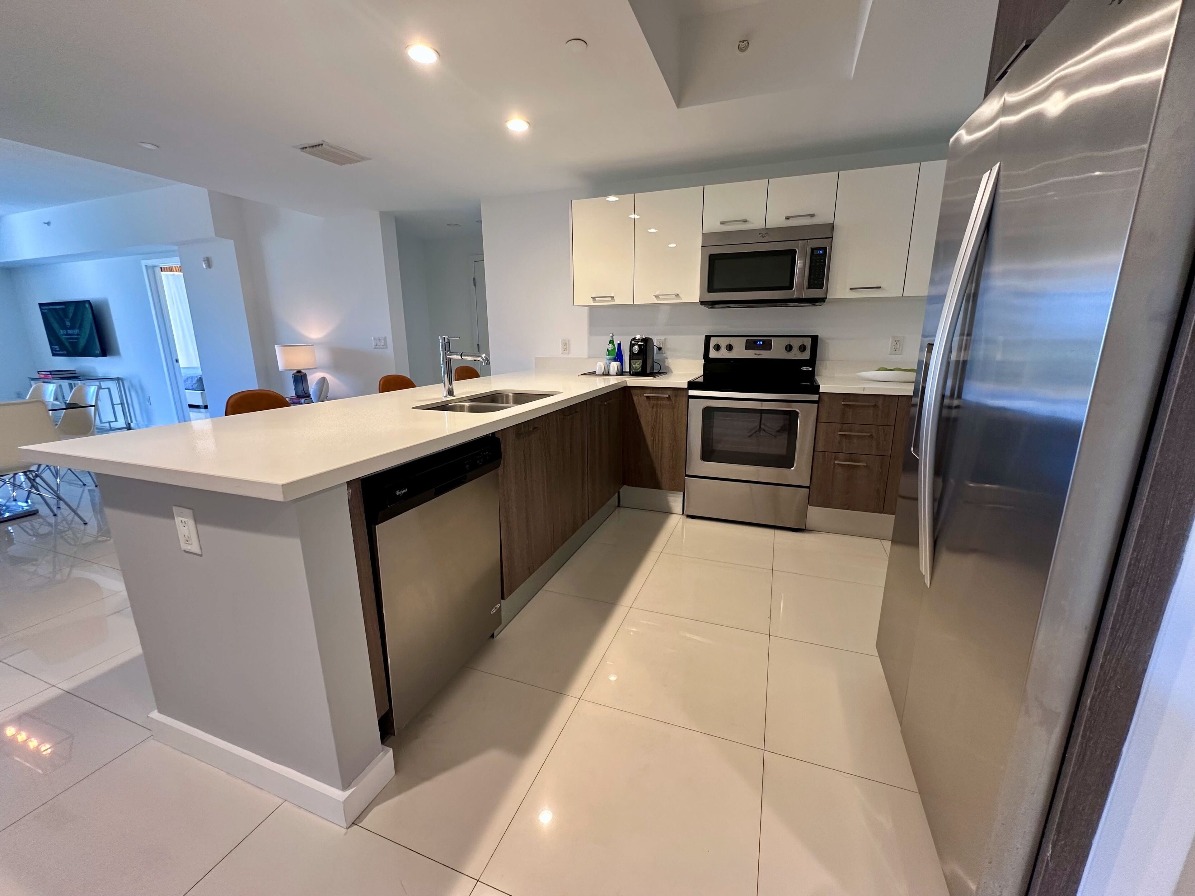 A modern kitchen with a central island, stainless steel appliances, and a dining area with a TV.
