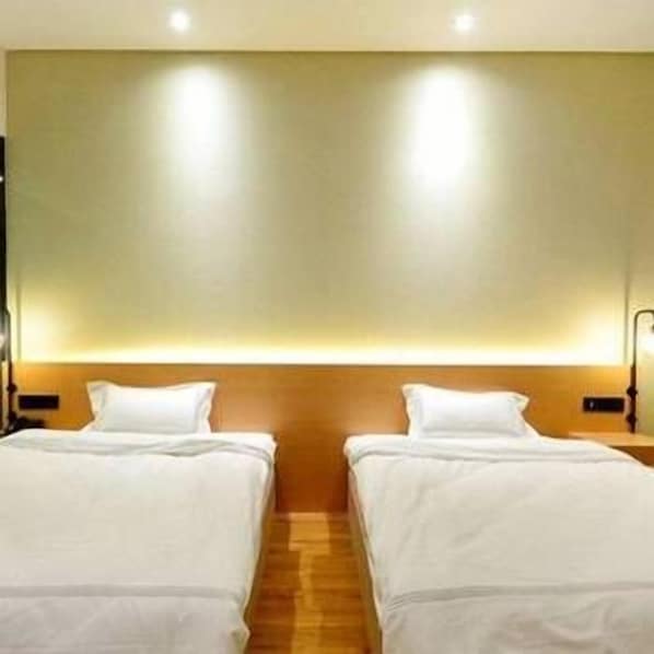 A hotel room with two beds, wooden headboards, and a wall-mounted light fixture. - Xingwei Hostel (Wuhan)
