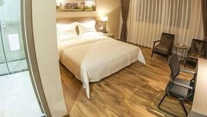 A hotel room with a bed, a desk, a chair, and a window with curtains. - Orsa Hotel (Jiangmen)