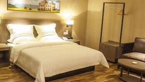 A hotel room with a bed, a chair, a desk, and a painting on the wall. - Orsa Hotel (Jiangmen)