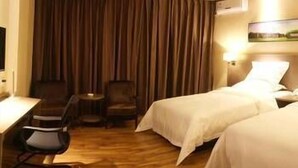 A hotel room with two beds, a desk, a chair, and a small table. - Orsa Hotel (Jiangmen)