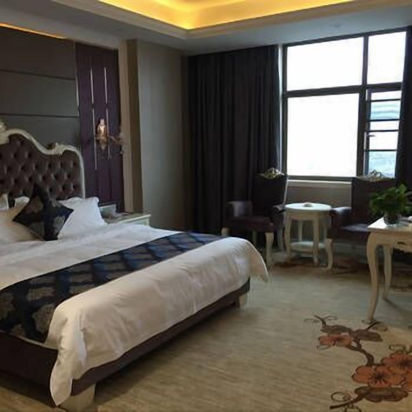 Une chambre d’hôtel avec un grand lit, une petite table, une chaise et une vue sur l’extérieur par une fenêtre.