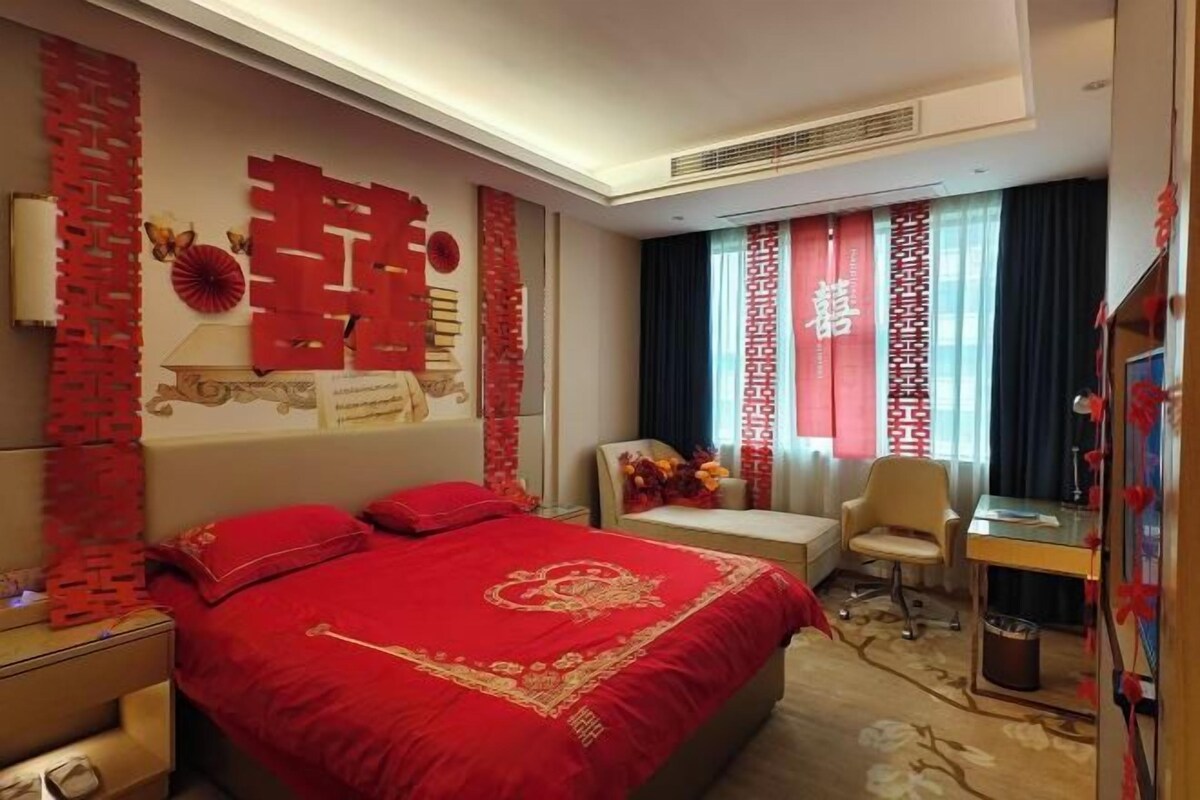 Una habitación de hotel con una cama, un escritorio, una silla y elementos decorativos.
