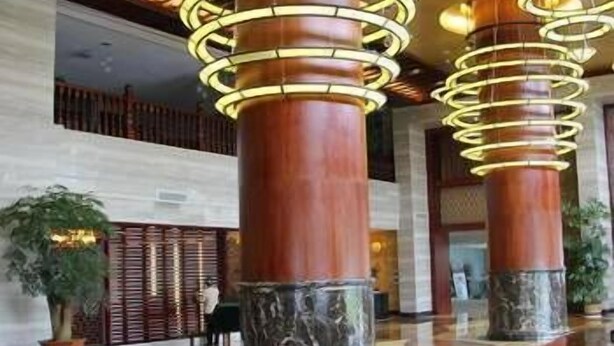 A lobby with marble columns and a wooden floor.