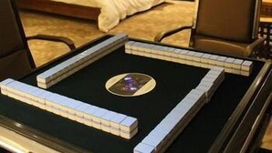 A hotel room with a neatly made bed, a bedside table with a lamp, and a chair.