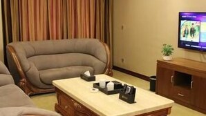 A living room with a brown leather sofa, a wooden coffee table, and a television on a wooden stand.