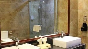 A bathroom with two sinks, a large mirror, and a shower area.