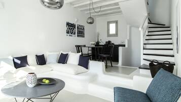 Un salon moderne avec un canapé blanc, une table basse ronde et un escalier menant à l’étage supérieur.