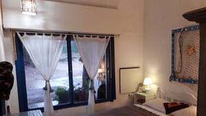 Ein Schlafzimmer mit Bett, Nachttisch, Lampe und einem Fenster mit Vorhängen.