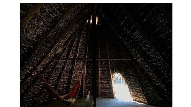 A thatched-roof structure with a central opening leading to an outdoor area.