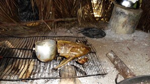 A rustic outdoor cooking setup with a grill, a metal pot, and a large bowl.