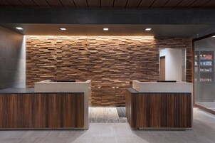 Uma área de recepção com design moderno, destacando uma parede de madeira e dois balcões de atendimento.