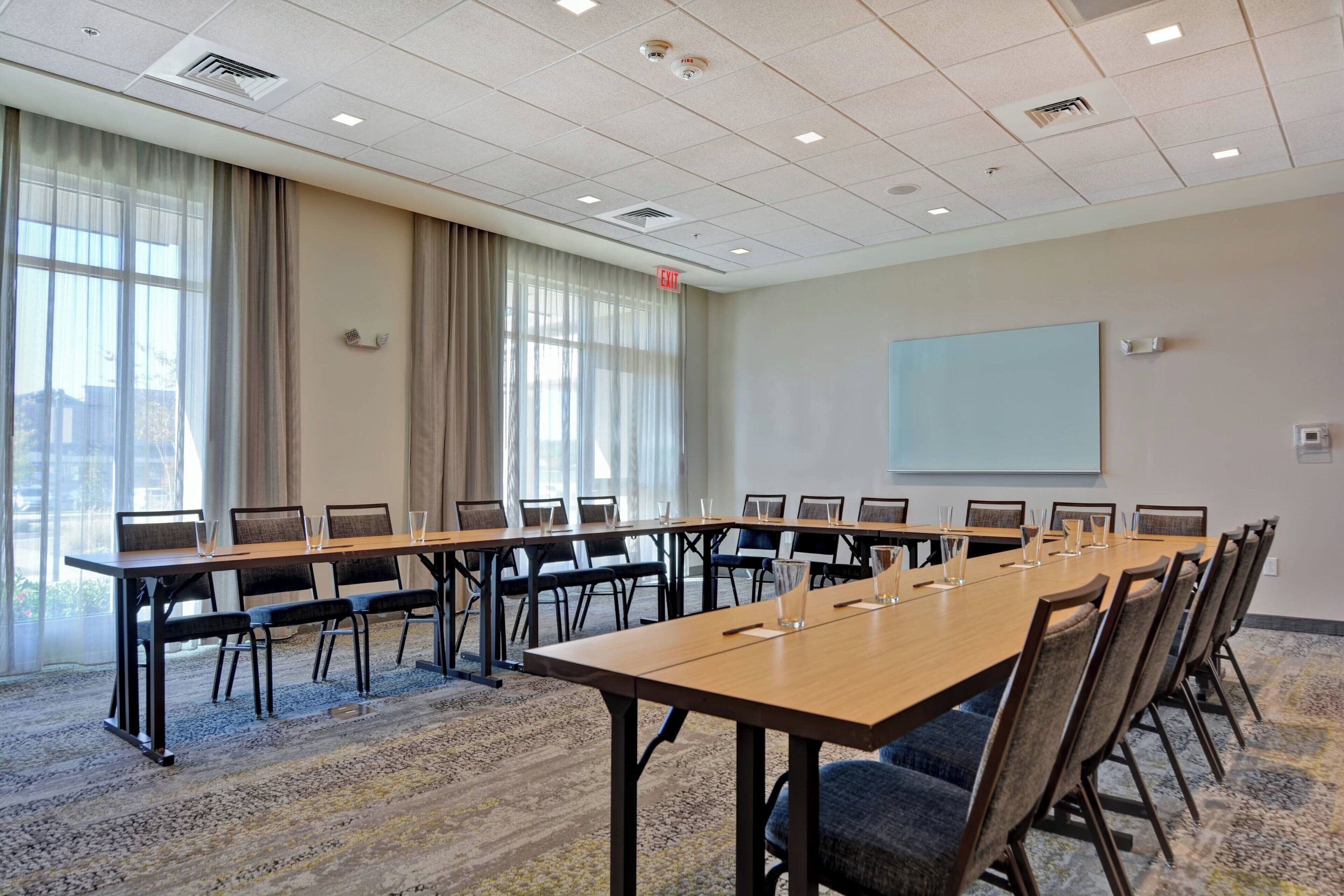 A conference room with a long table, chairs, and a projector screen.