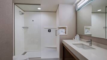 Een moderne badkamer met een douchecabine van glas, een witte wastafel en een grote spiegel.