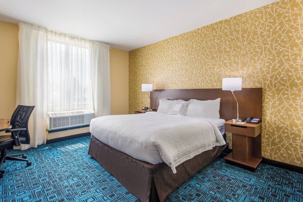 A hotel room with a large bed, two bedside tables, a desk, and a chair.