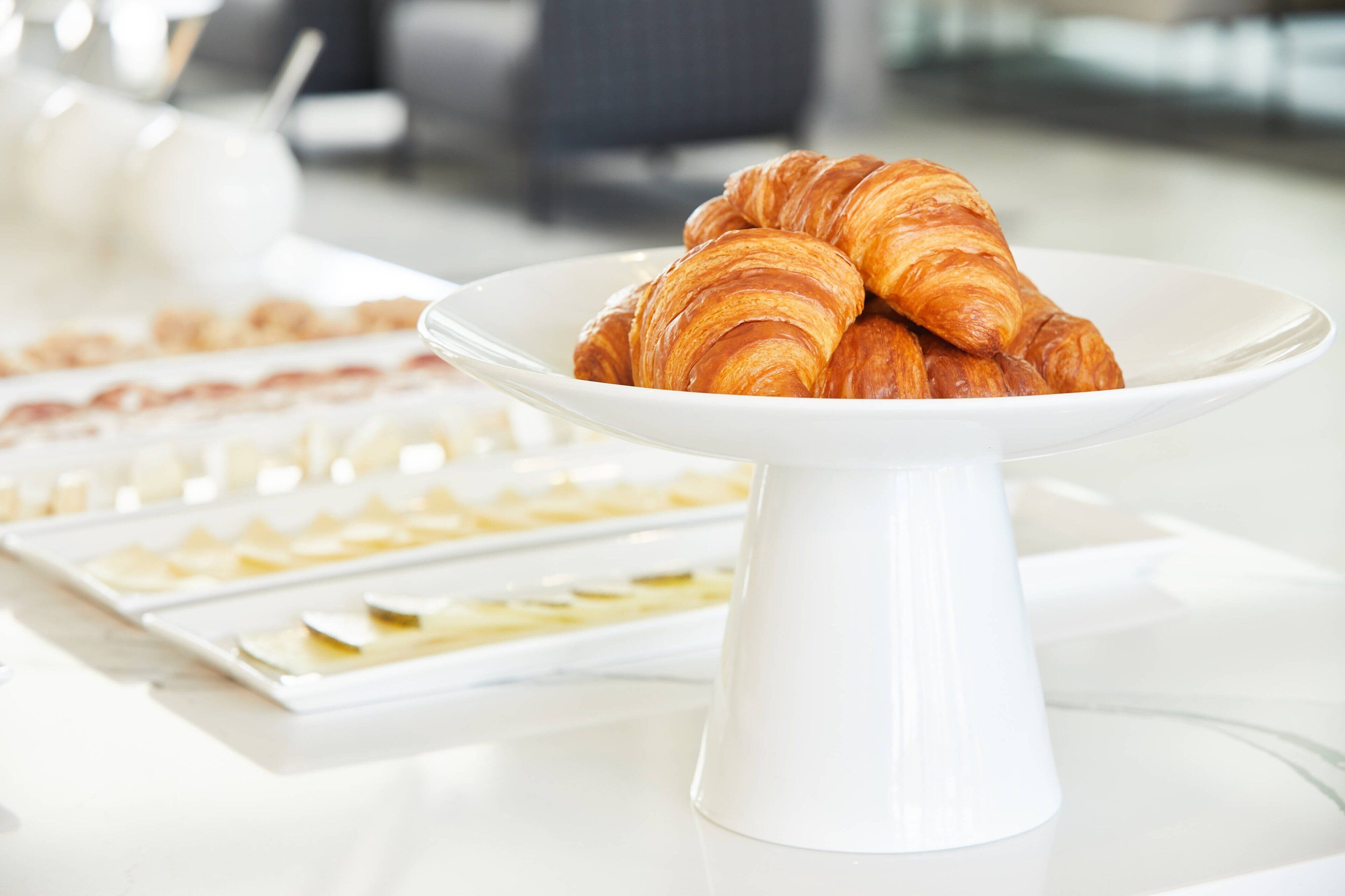 Un plato blanco con cruasanes sobre una mesa blanca.