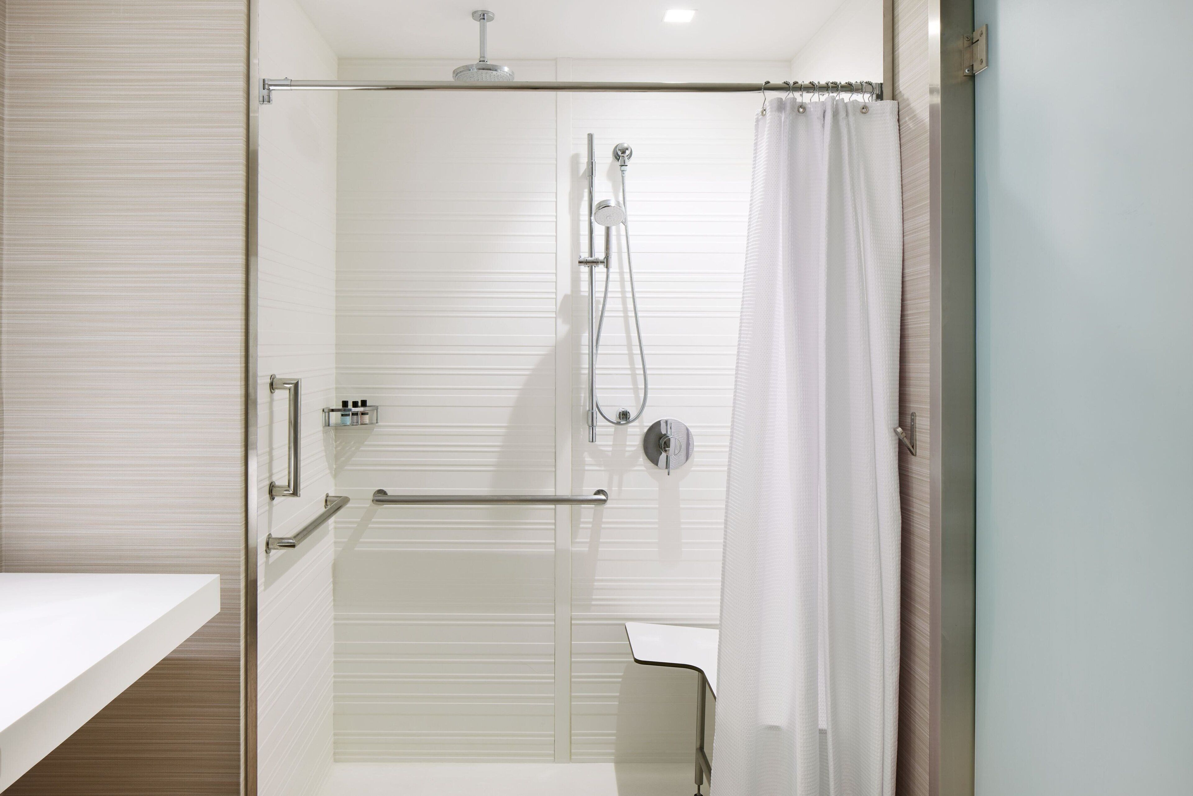 A modern bathroom with a glass shower enclosure, a white sink, and a towel rack.