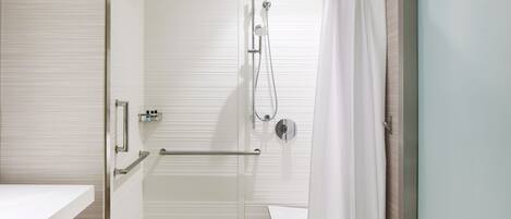 A modern bathroom with a glass shower enclosure, a white sink, and a towel rack.