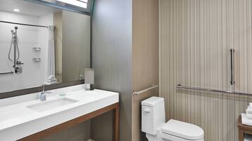 A modern bathroom with a white sink, mirror, and toilet.