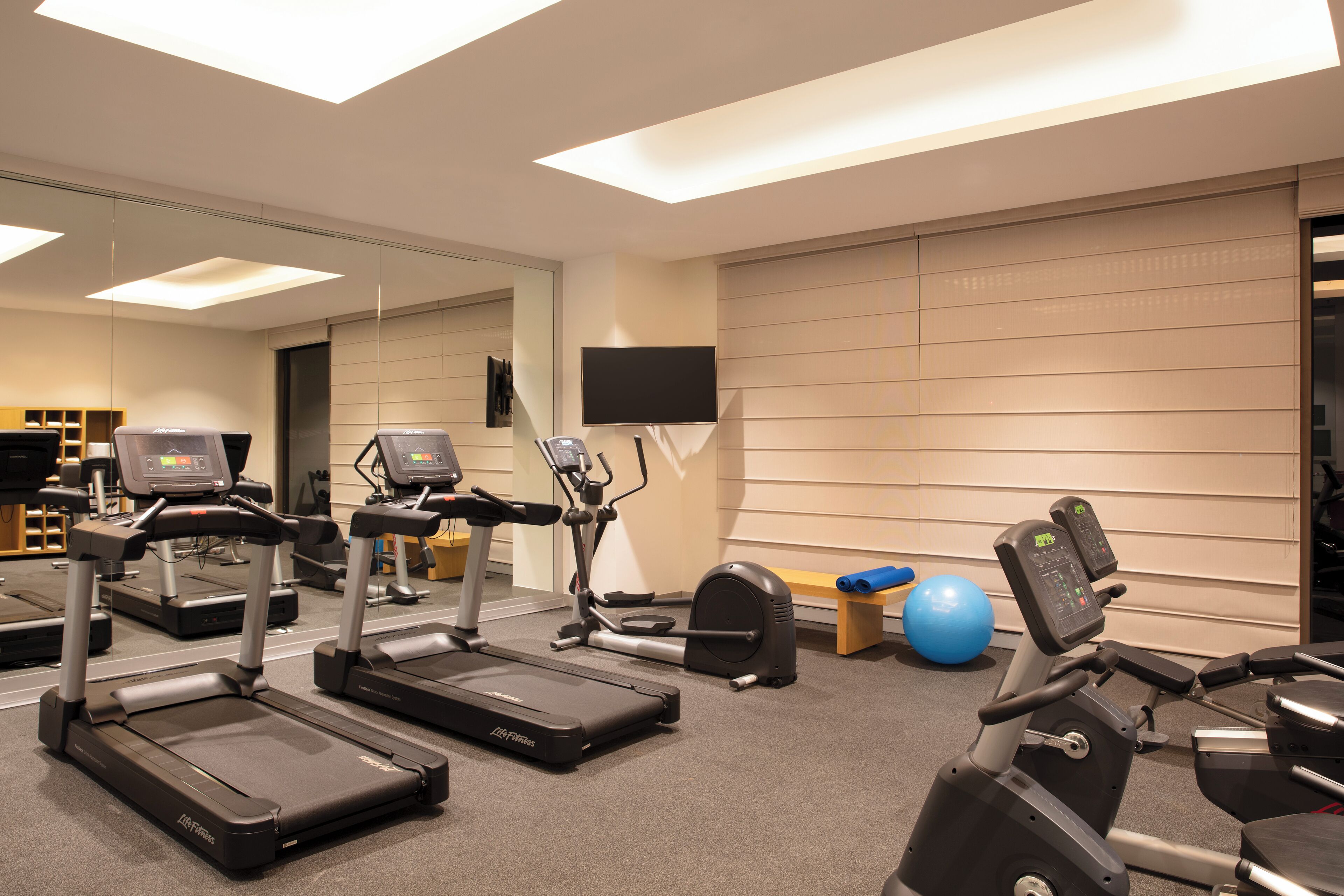 A gym with treadmills, elliptical machines, and exercise balls.