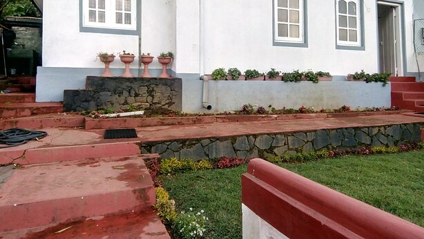 A white building with a stone foundation, red steps, and potted plants on the front. - White Cottage Nuwara Eliya (Nuwara Eliya)