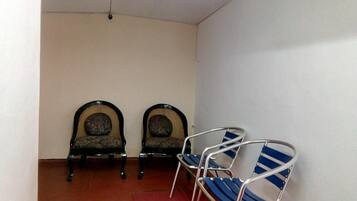 Ein Zimmer mit zwei hölzernen Stühlen mit gepolsterten Rückenlehnen sowie einem Stuhl aus Metall mit blau-weißen Streifen.