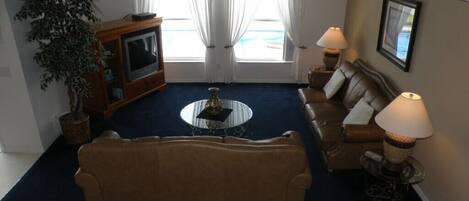 A living room with a sofa, coffee table, TV, and lamps.