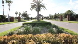 Un área ajardinada con una palmera en el centro, un pabellón y un camino pavimentado.