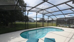 Una piscina esterna con area coperta, circondata da una recinzione in metallo e due lettini.