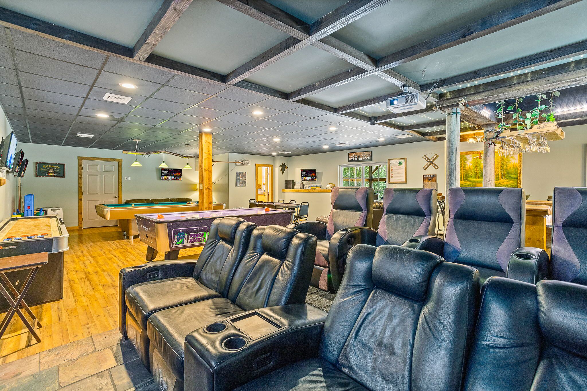 A billiards room with pool tables, comfortable seating, and a projector screen.