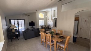 Amplia sala de estar con sofá, televisión y mesa de comedor con sillas.