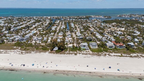 Luchtbeeld van een kustgebied met huizen, een strand en een jachthaven.