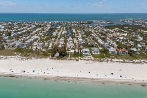 An aerial view of a coastal residential area with houses, a beach, and a marina.