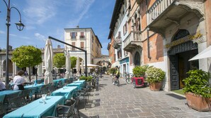 An outdoor café with tables and chairs, a cyclist, and a building with a sign.