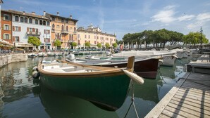 A marina with boats docked, a wooden dock, and historic buildings in the background.