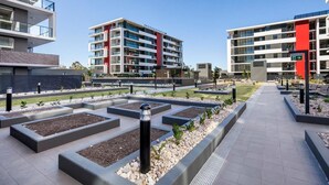A modern apartment complex with multiple buildings, outdoor pathways, and landscaped gardens. - Astra Apartments Wollongong (Wollongong)