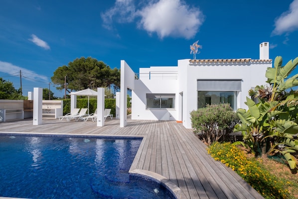 A modern house with a swimming pool, white exterior, and a wooden deck.