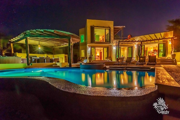 A modern two-story house with a swimming pool, outdoor seating, and a covered patio area.