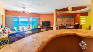 A spacious living area with a large TV, comfortable seating, and a view of the ocean.